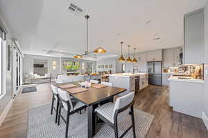 Dining space with dark wood-type flooring, ceiling fan, a raised ceiling, and recessed lighting