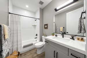 Bathroom with vanity, shower / tub combo, dark wood-style flooring, and recessed lighting