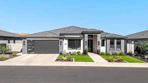 Prairie-style home featuring driveway, stucco siding, an attached garage, and a front yard