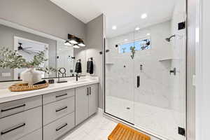 Full bathroom with double vanity, light marble finish flooring, and a marble finish shower