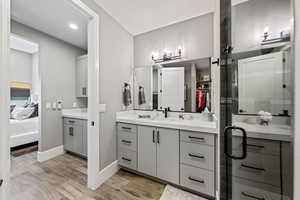 Ensuite bathroom with wood finish floors, vanity, a stall shower, a walk in closet, and recessed lighting
