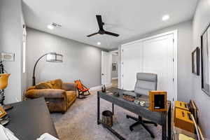 Carpeted office space with a ceiling fan and recessed lighting