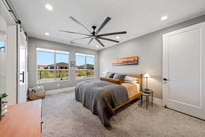 Bedroom featuring a barn door, light carpet, ceiling fan, and recessed lighting