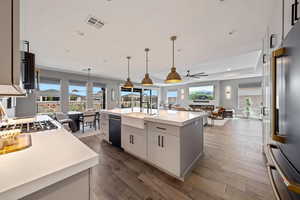 Kitchen with open floor plan, high end refrigerator, dark wood-style flooring, and an island with sink