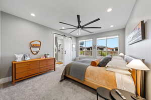 Bedroom with a barn door, light carpet, a ceiling fan, ensuite bathroom, and recessed lighting