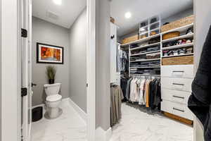Bathroom featuring light marble finish flooring and a walk in closet