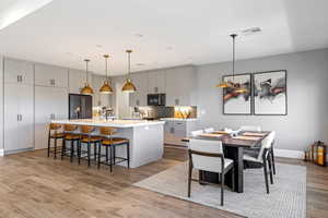 Kitchen featuring gray cabinetry, a breakfast bar, a large island with sink, and light wood-type flooring