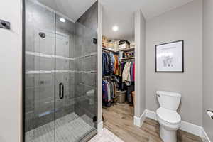 Bathroom featuring a stall shower, light wood-style floors, a spacious closet, and recessed lighting