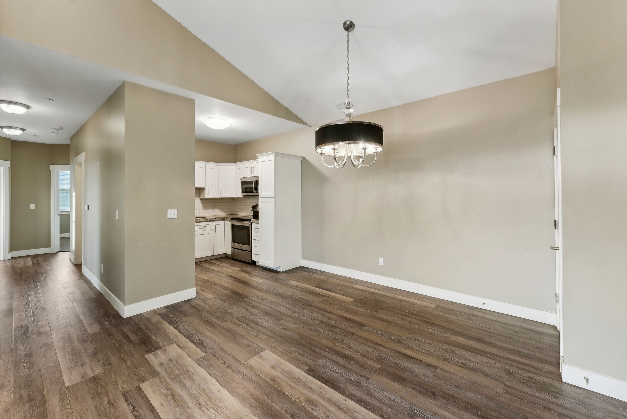 Unfurnished dining area with lofted ceiling, dark wood-type flooring, and suspended lighting