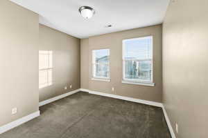 Unfurnished room featuring dark carpet and baseboards