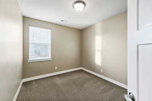 Unfurnished room with healthy amount of natural light and dark carpet