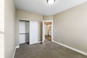 Unfurnished bedroom featuring dark colored carpet and a closet