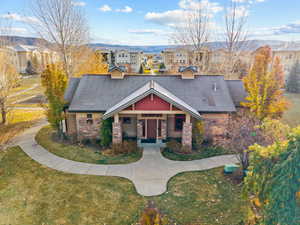 Craftsman-style house featuring covered porch, a front yard, roof with shingles, and stone siding