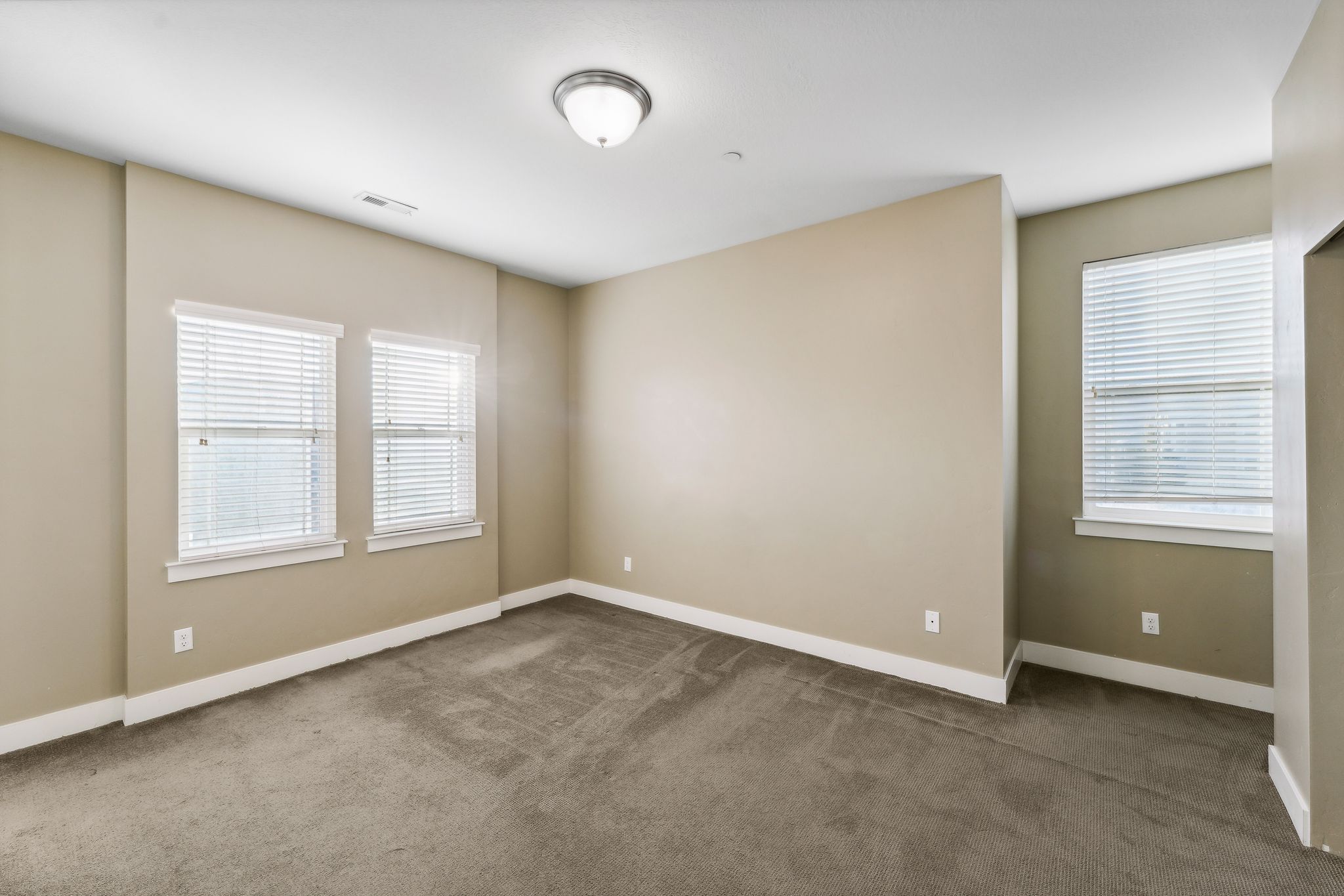 Spare room featuring dark colored carpet and baseboards
