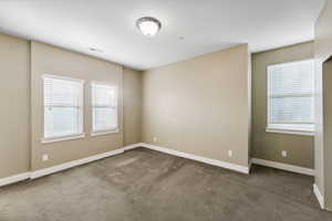 Spare room featuring dark colored carpet and baseboards