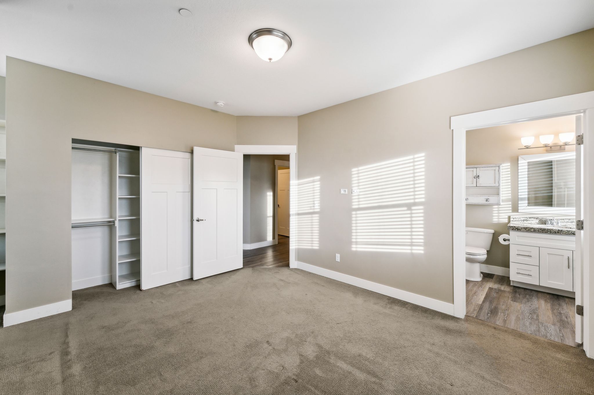 Unfurnished bedroom with a closet, dark colored carpet, and ensuite bathroom