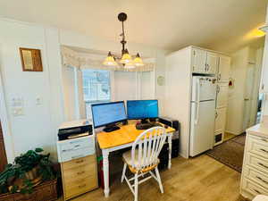 Office with light wood-style flooring and suspended lighting