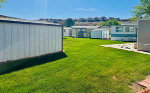 View of grassy yard with a shed and a residential view