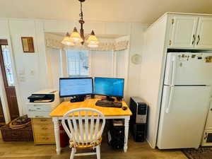 Office area with light wood-style floors, crown molding, and suspended lighting