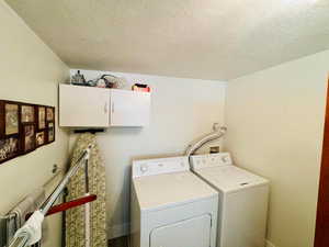 Laundry room featuring cabinet space, independent washer and dryer, and a textured ceiling