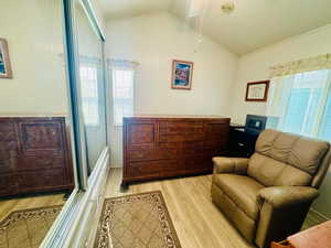 Sitting room featuring light wood-style floors, ornamental molding, and lofted ceiling