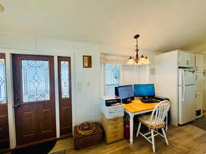 Foyer entrance featuring light wood-style flooring and suspended lighting