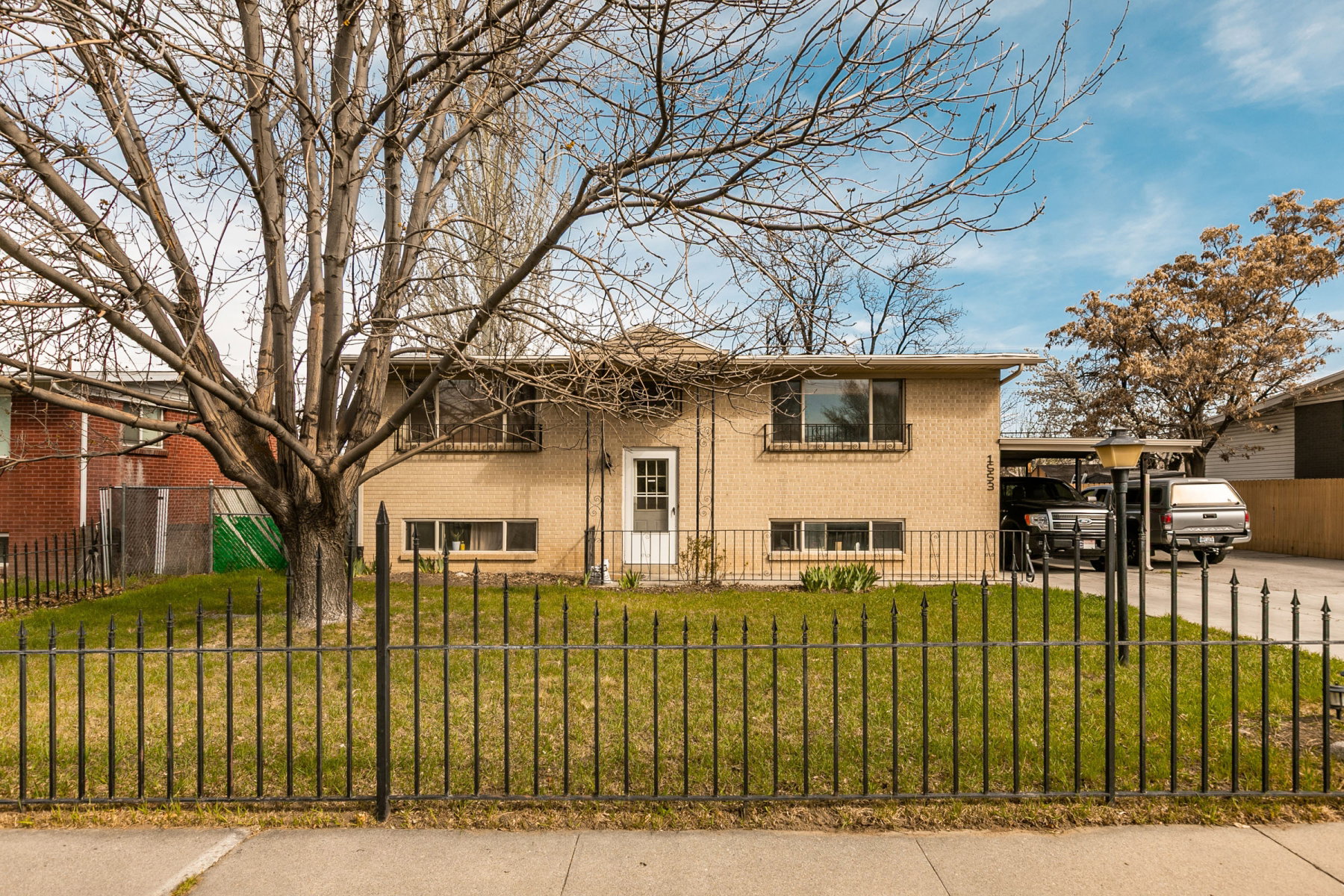 Bi-level home with brick siding, a fenced front yard, and an attached carport