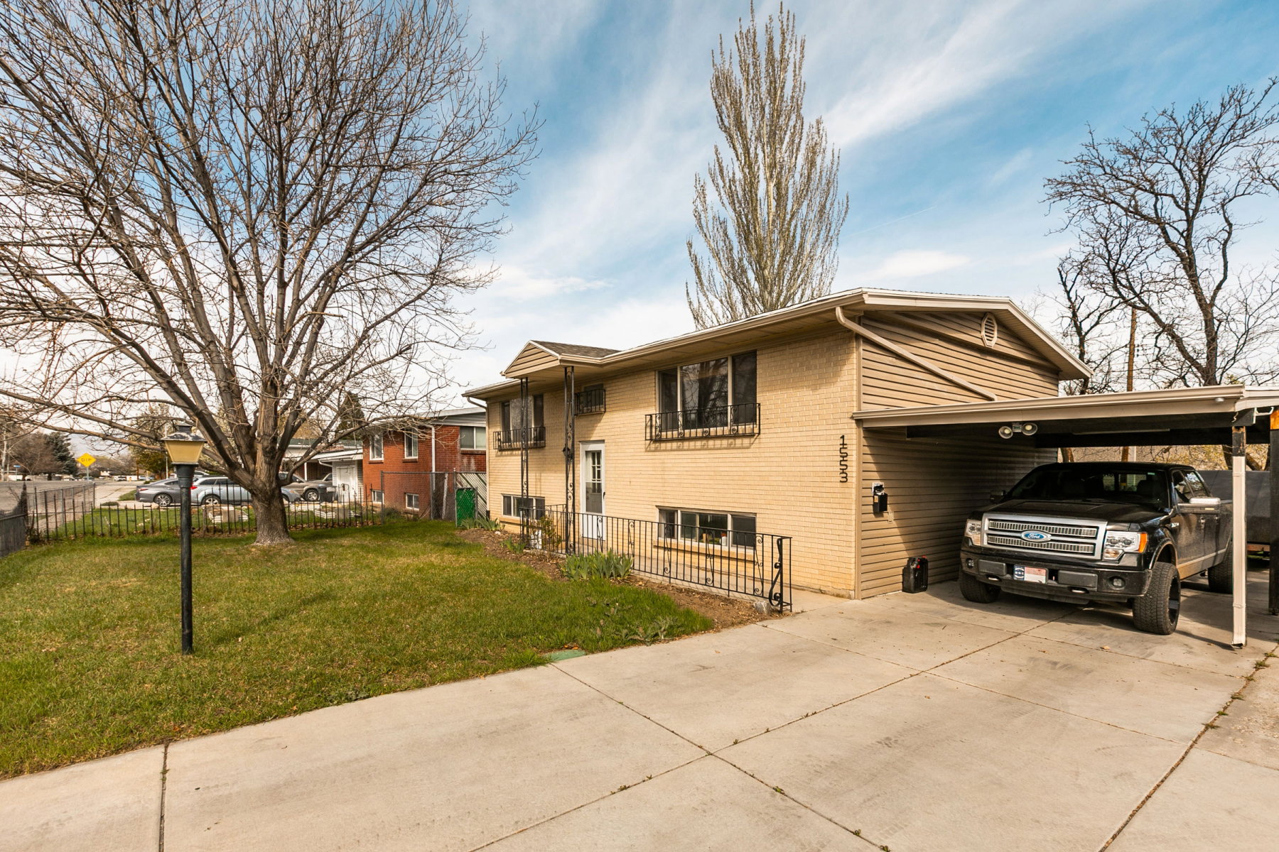 Bi-level home featuring a carport, driveway, and brick siding