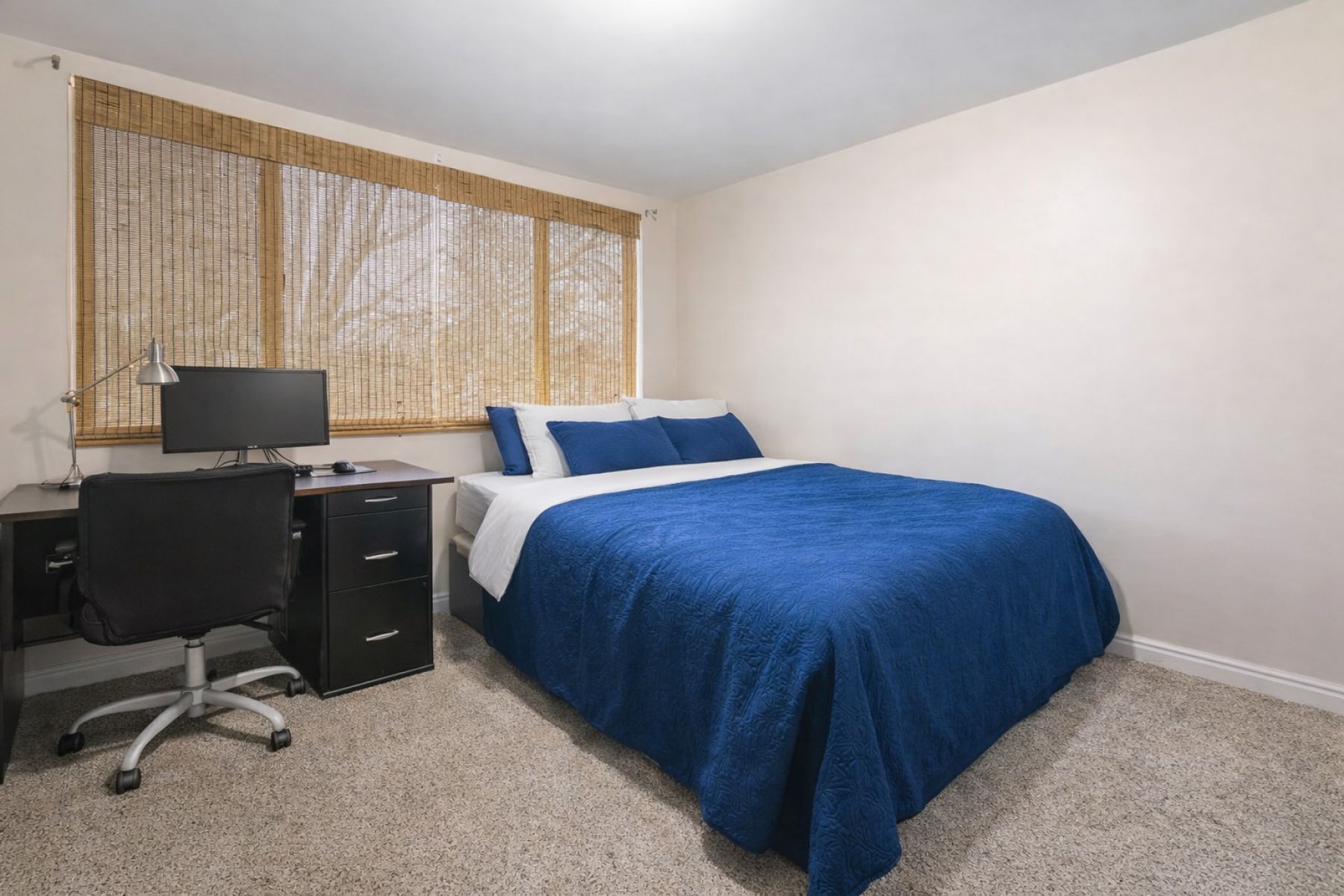 Bedroom with a desk and light colored carpet