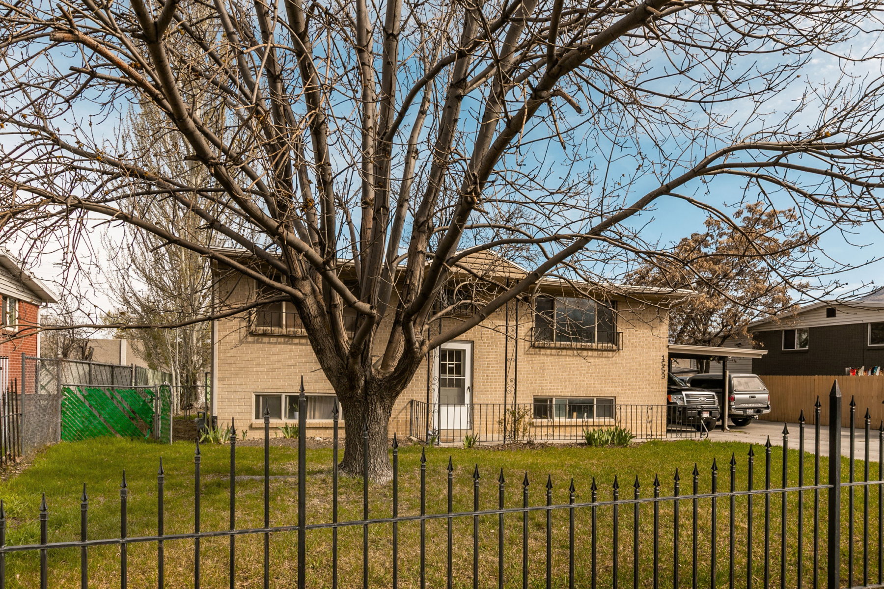 View of front of house featuring brick siding, a fenced front yard, and a carport