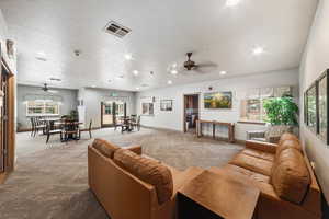 Carpeted living room featuring a ceiling fan and recessed lighting