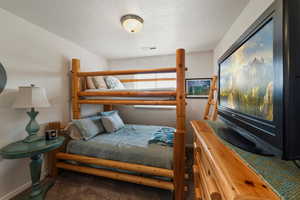 Bedroom featuring dark colored carpet and a textured ceiling