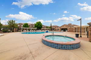 Community pool featuring a patio, a hot tub, and a residential view