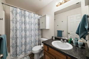 Bathroom featuring vanity, shower / bathtub combination with curtain, and a textured ceiling