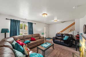 Carpeted living room featuring stairs and a textured ceiling