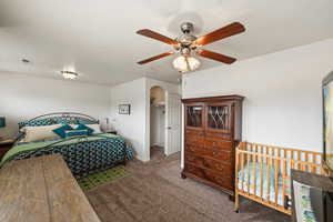 Bedroom featuring a spacious closet, arched walkways, dark colored carpet, and ceiling fan