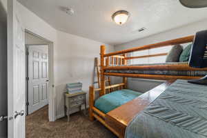 Bedroom with dark carpet and a textured ceiling
