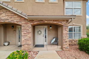 Doorway to property featuring stone siding and stucco siding