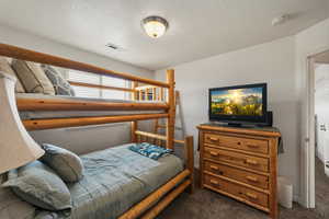 Bedroom featuring dark carpet and a textured ceiling