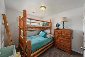 Bedroom featuring a textured ceiling and dark carpet