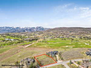 Aerial view of residential area with property parcel outlined and mountains