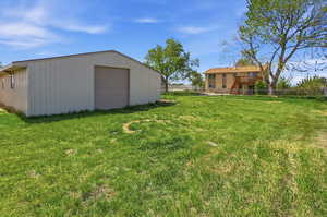 View of yard featuring a garage and an outbuilding