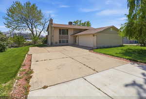 View of front of property featuring a front lawn, brick siding, an attached garage, and concrete driveway