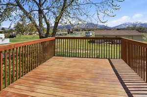 Wooden terrace featuring a mountain view, a residential view, and a lawn