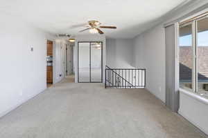 Spare room with ceiling fan, light carpet, and a textured ceiling