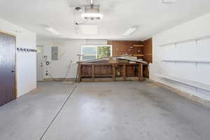 Garage featuring electric panel, a workshop area, and a garage door opener