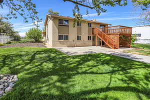 Rear view of property featuring a chimney, a wooden deck, and a patio