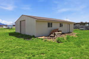 Rear view of property featuring a garage, an outbuilding, a mountain view, and a shingled roof