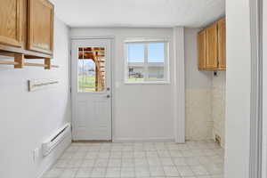 Entryway featuring a baseboard heating unit and a textured ceiling