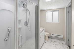Full bathroom with baseboard heating, a shower stall, vanity, light marble finish floors, and a textured ceiling